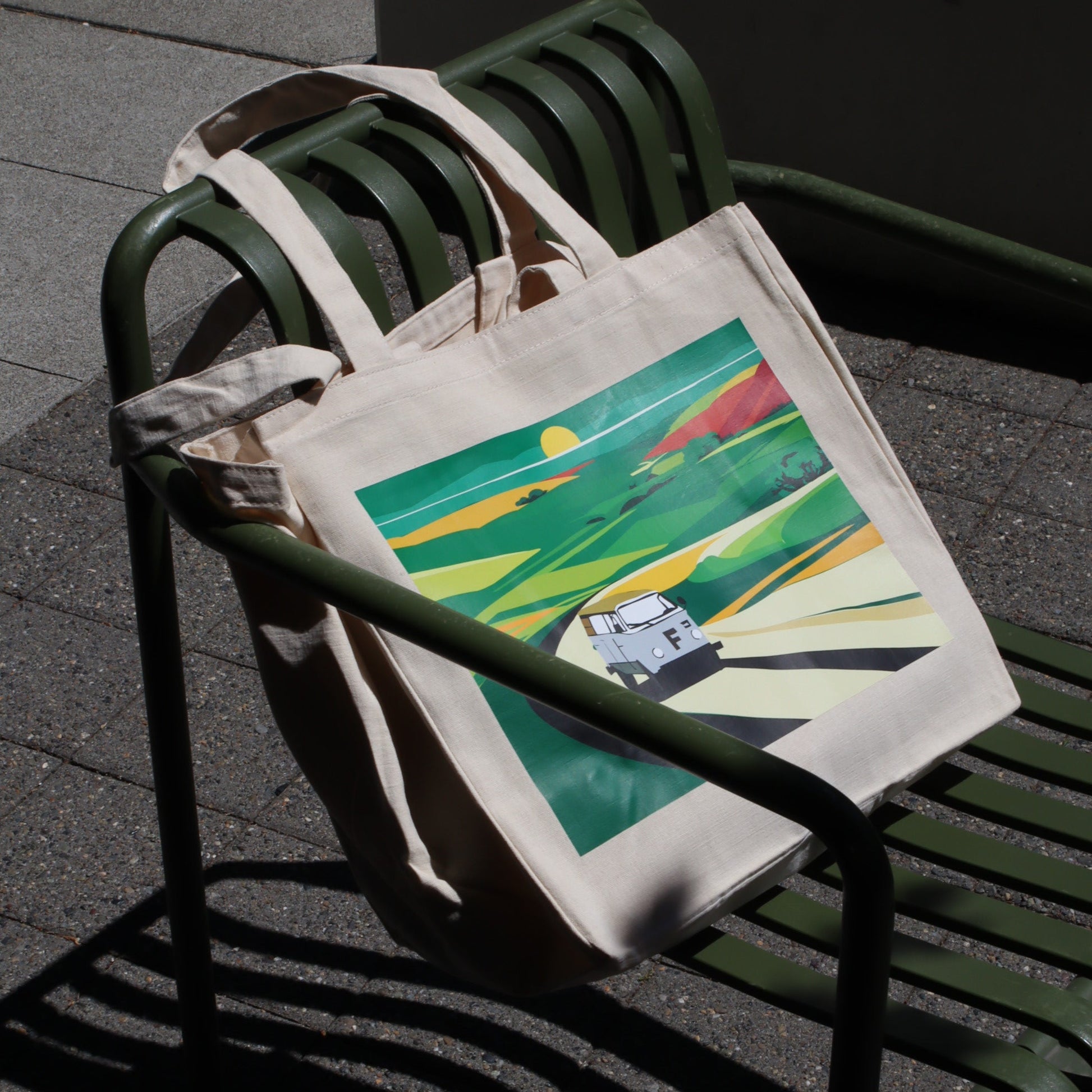 Tote bag with colorful design on a green metal bench