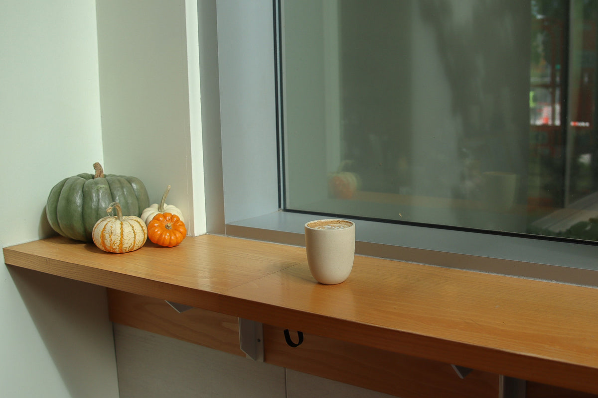 hot coffee with a latte in a cup sitting on a table next to fall pumpkins at the Fulcrum Cafe 