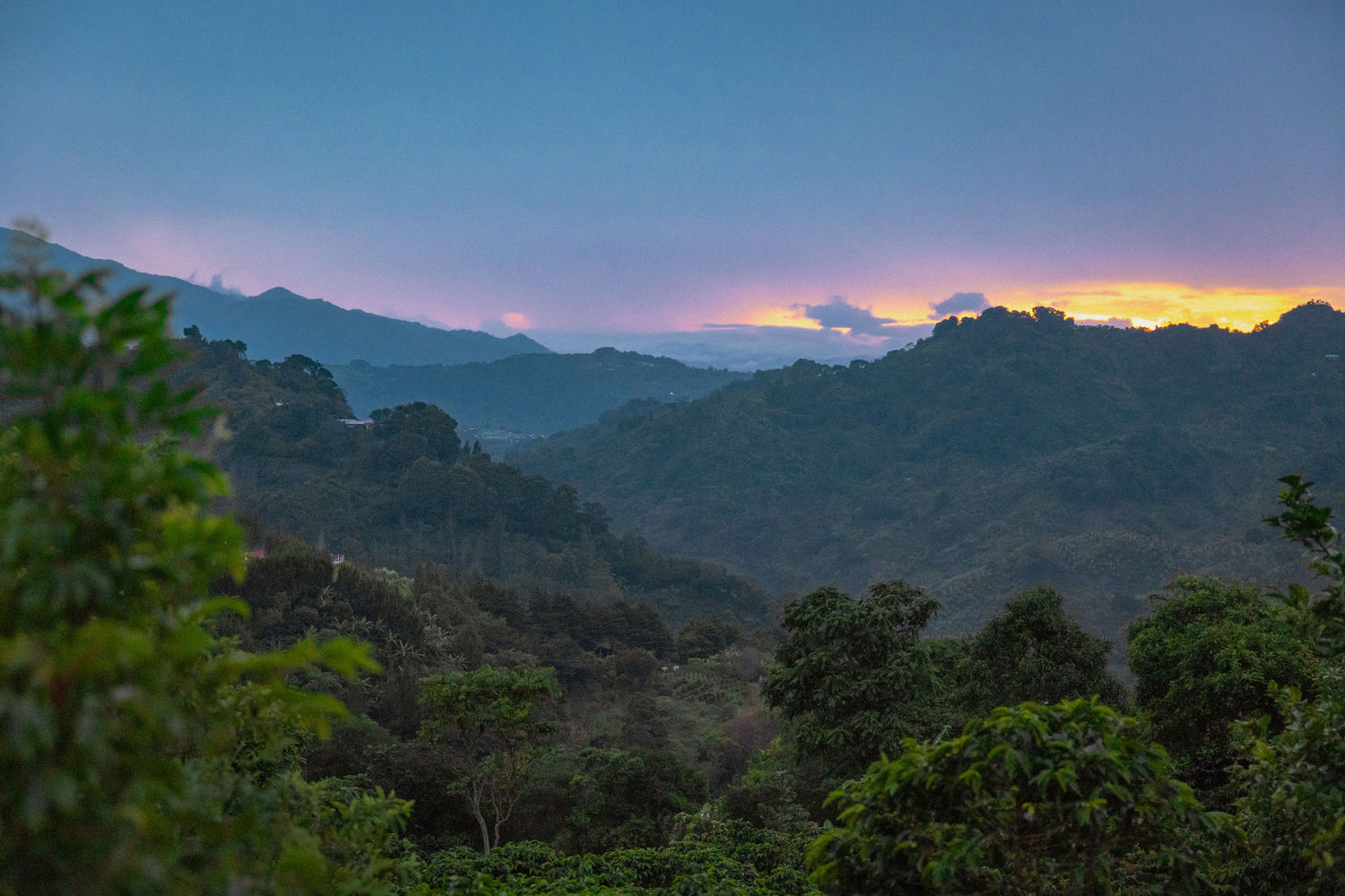 Hazy mountain landscape with a colorful sky at sunset.
